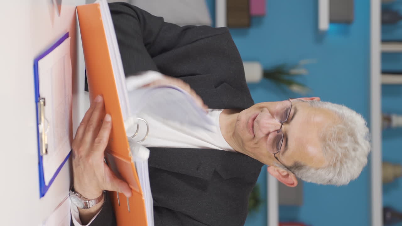 vídeo vertical de un trabajador de oficina en casa mirando archivos de papeleo.