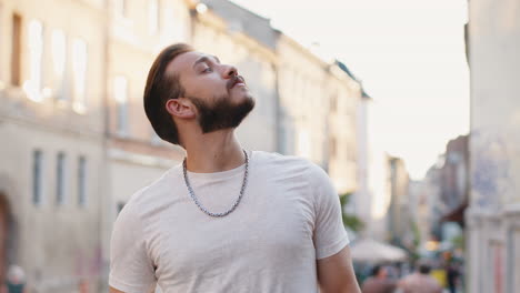 portrait of young man guy tourist walking in urban city street, smiling having positive good mood