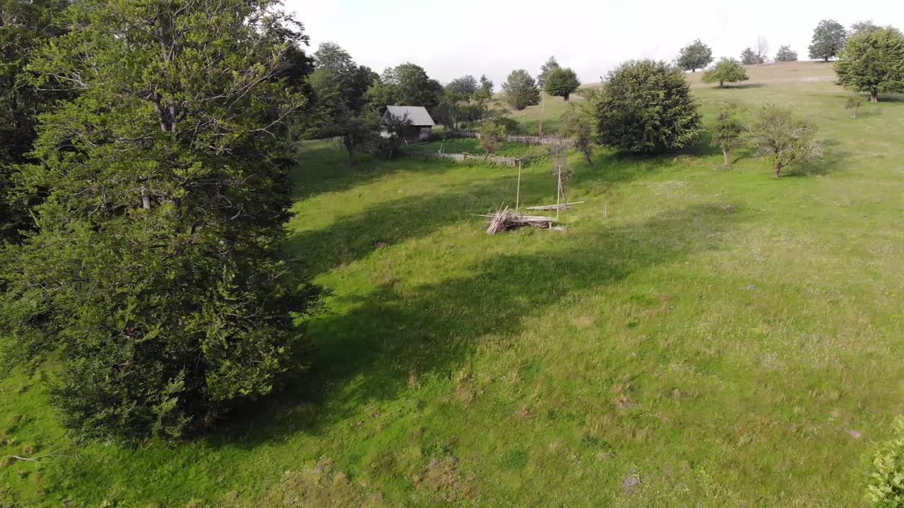 pequeña casa en medio de la naturaleza en un prado rodeado de bosque, imágenes de drones