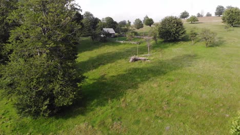 Kleines-Haus-Mitten-In-Der-Natur-Auf-Einer-Von-Wald-Umgebenen-Wiese,-Drohnenaufnahmen