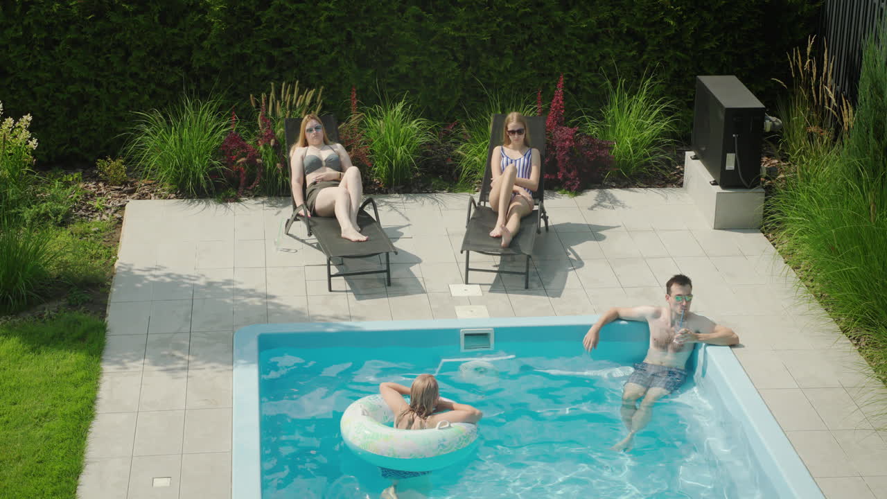 Familie slapper af ved poolen og nyder en god hvile på en varm sommerdag