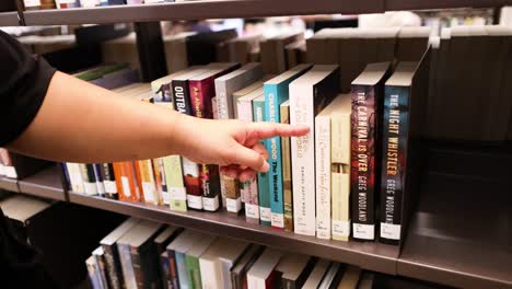 hand choosing a book from library shelf