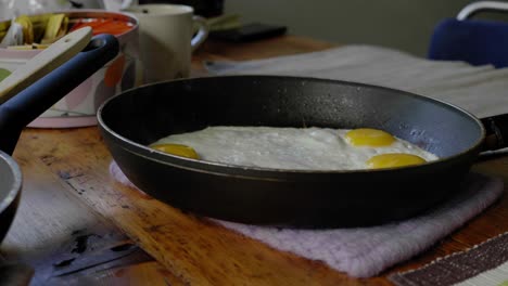 fresh fried eggs steam in skillet on wooden table at home, close-up