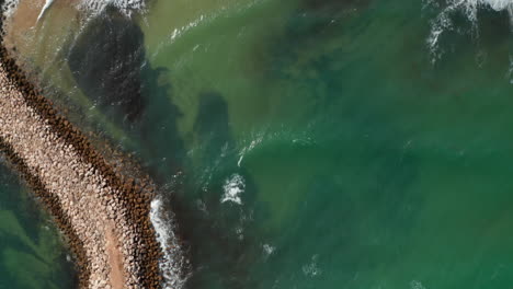 Aerial-birds-eye-overhead-top-down-view-of-breakwater-barrier-in-Lagos,-Portugal,-drone-flying-forward-reveals-beautiful-sandy-beach-coastline,-day