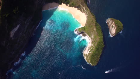 drone flying forward above kelingking beach on nusa penida island green peninsula yellow sand