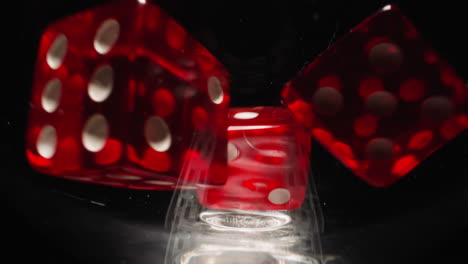 Red-cubes-with-white-dots-falling-into-wineglass-at-light