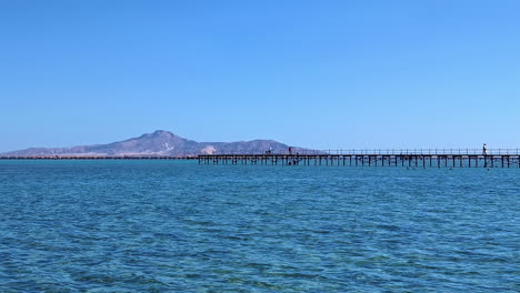 largo muelle de madera de un hotel en egipto, vista desde un barco en movimiento