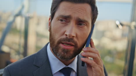 retrato empresario confiado hablando teléfono inteligente en la terraza. vista soleada de la ciudad