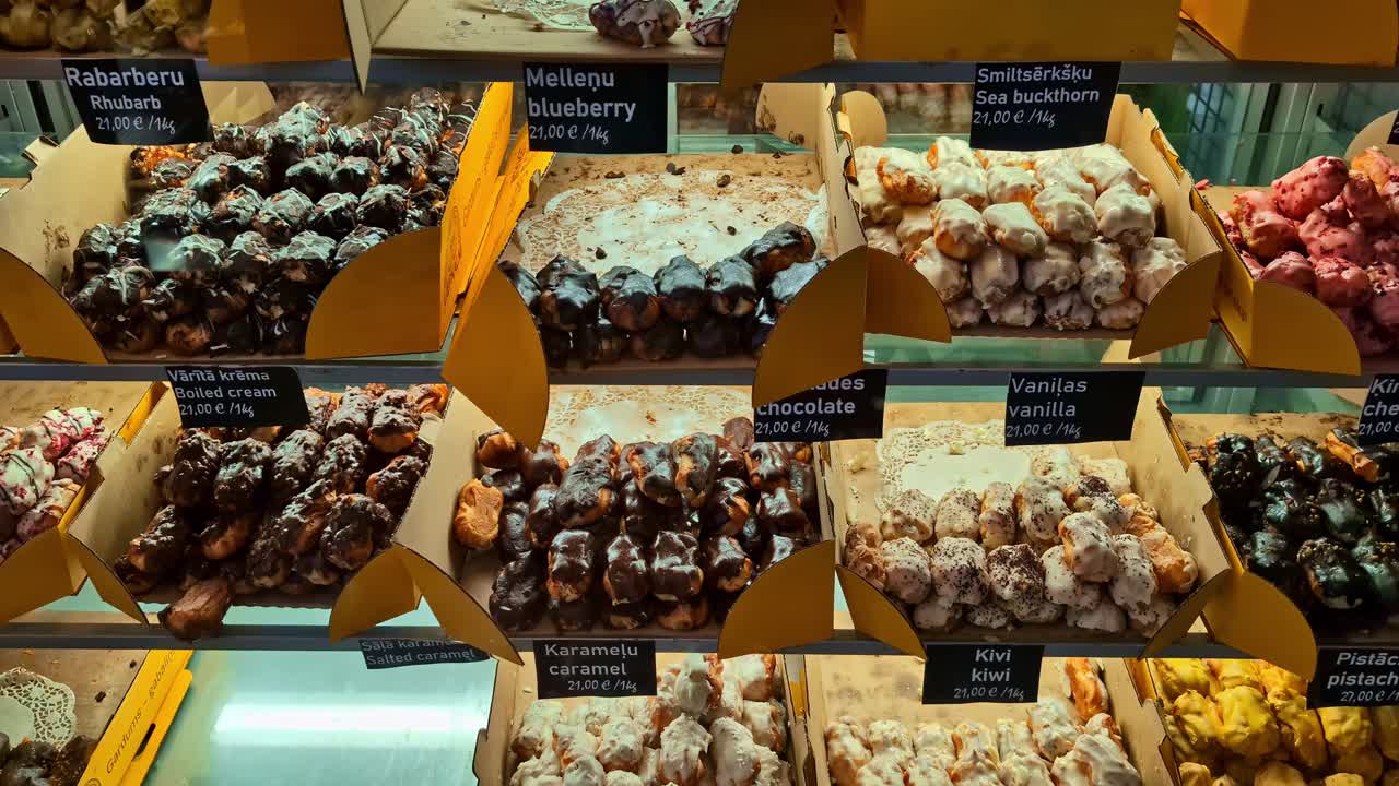 Colorful display of gourmet sweets and confectionery with various flavors like rhubarb, caramel, and pistachio in a Latvian store
