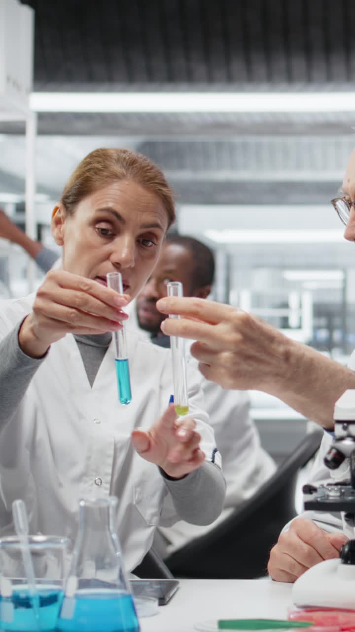 Vertical video Lab team leader teaching intern to analyze liquid polymer properties
