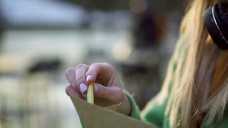 mujer comiendo papas fritas al aire libre en la feria callejera de invierno con ketchup