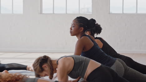 yoga-class-beautiful-group-of-women-practicing-sleeping-pigeon-pose-enjoying-healthy-lifestyle-stretching-flexible-body-in-fitness-studio