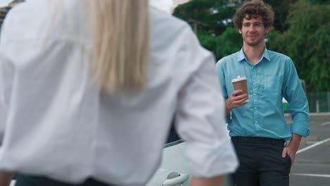 Progressive-businessman-and-businesswoman-leaning-on-EV-car-and-charging-point.