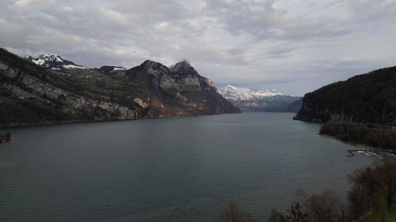 pan aérea por encima de la costa y el lago walen aguas azotadas por el viento con hermosas cordilleras de montaña cubiertas de nieve