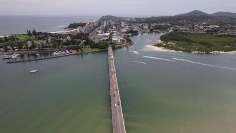 daytime traffic on road bridge spanning coolongolook river in forster, new south wales, australia. aerial shot