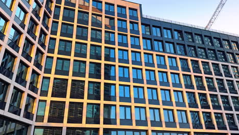 modern facade of the high-rise multi-storied building. neighboring building reflects in the windows. low angle view