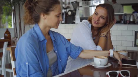 two women friends having coffee and conversation in a cafe