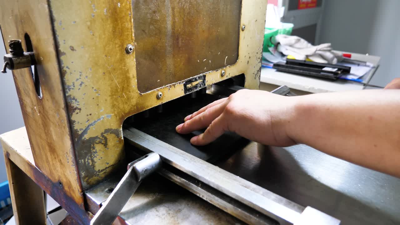 A skillful worker operates a cutting machine on PVC boards in a spectacle factory, highlighting precision and manual control. Danyang, Jiangsu Province, China.