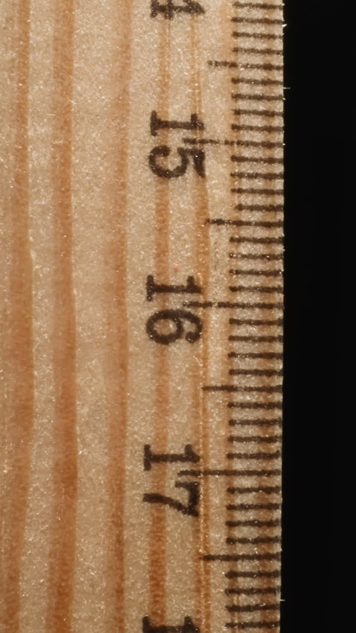 Wooden ruler marked with digits turning on black background. Straight strip from wood designed for drawing lines or measuring distances macro