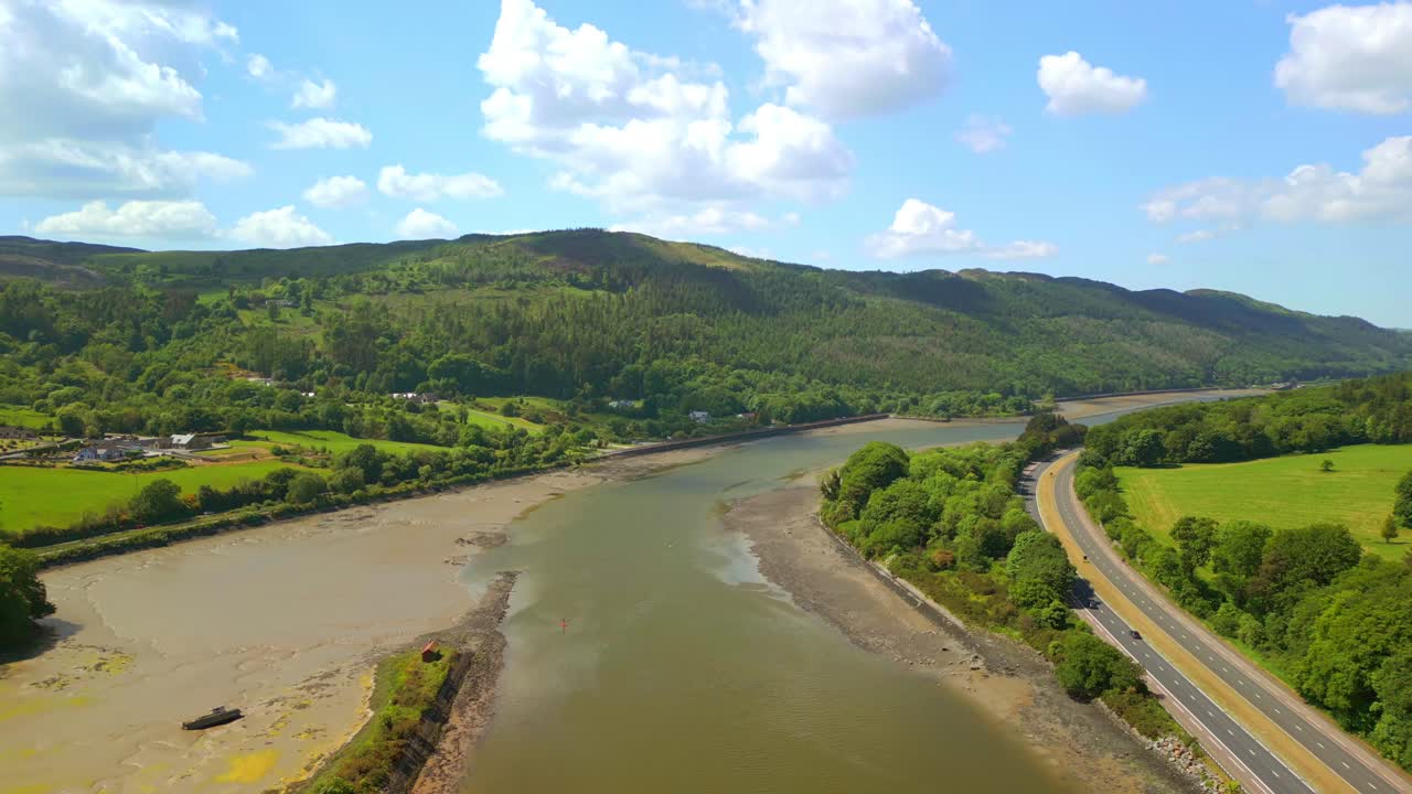 Wide, rising aerial video of the Newry River and Mourne Mountains in Warrenpoint, County Down, Northern Ireland, UK on a bright and sunny day. Filmed in 4K, 60FPS and with Rec709 color.