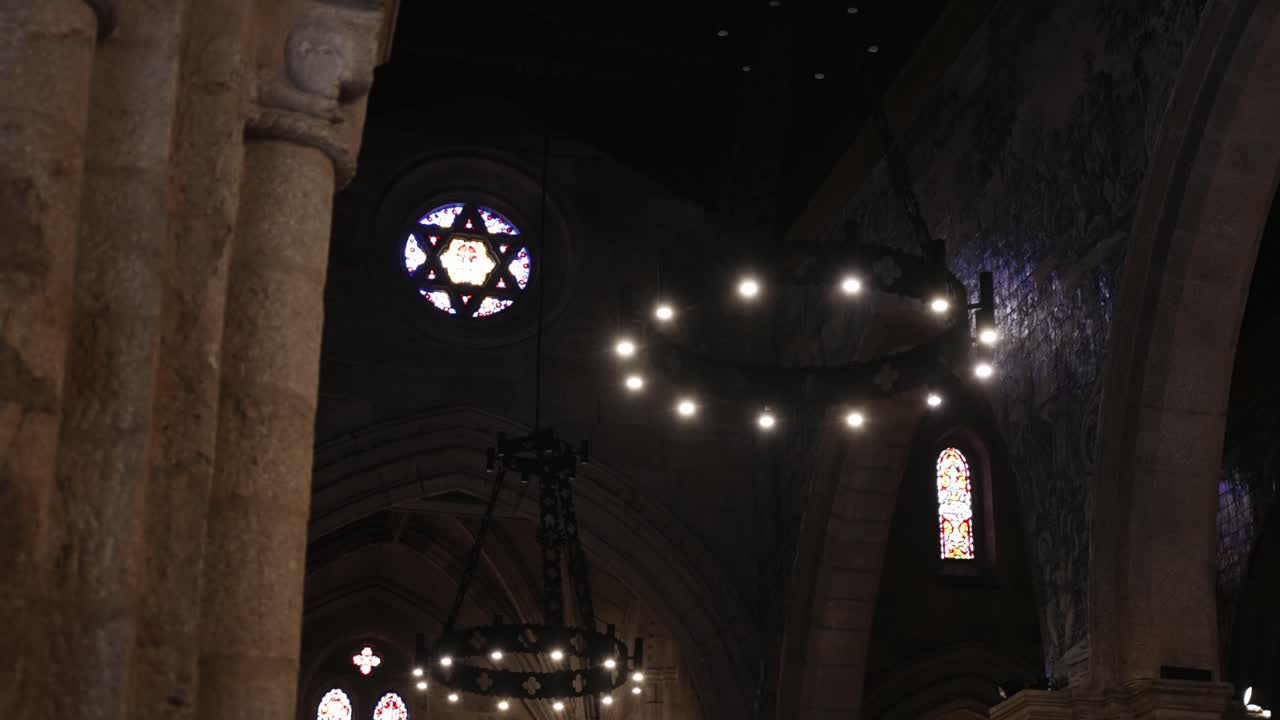 interior of a stone church with glowing chandeliers and a vivid star-shaped stained glass window