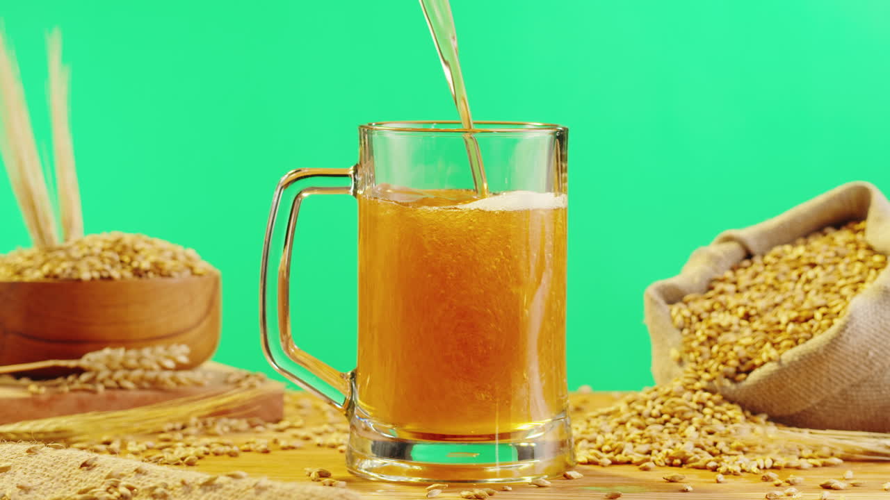 Pouring Beer into a Glass Mug with Wheat Grain Background