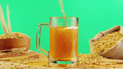 pouring beer into a glass mug with wheat grain background