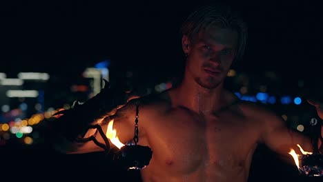 Young-blond-male-lowers-two-burning-pois-hanging-on-chains-Slow-motion-shot-Close-up-shot