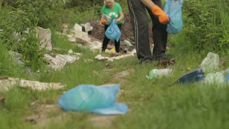 team of nature activists in eco t-shirts picking up plastic trash in park. recycle, earth pollution