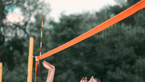 women competing in a professional beach volleyball tournament. a defender attempts to stop a shot during the 2 women international professional beach volleyball.