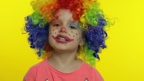 Little-child-girl-clown-in-colorful-wig-tells-something-interesting.-Having-fun,-smiling.-Halloween