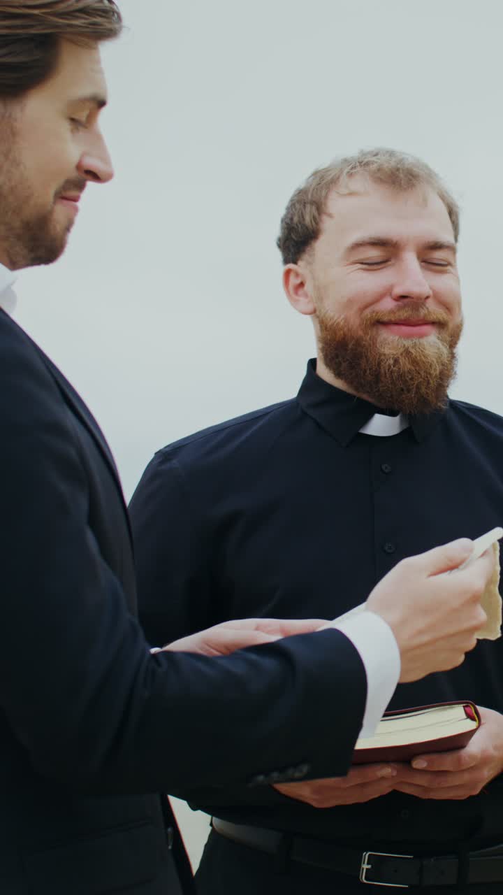 Priests reading a book outdoors