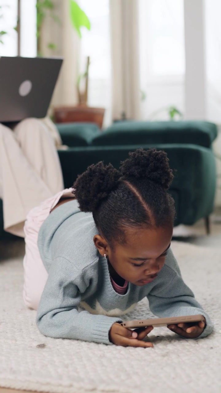 Young Black Girl Playing on Smartphone on Living Room Floor