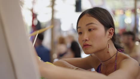 young woman concentrates on painting outdoors