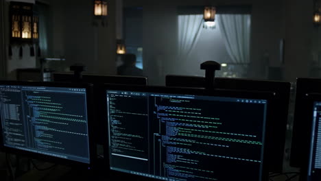 computer monitors displaying code in a dimly lit office