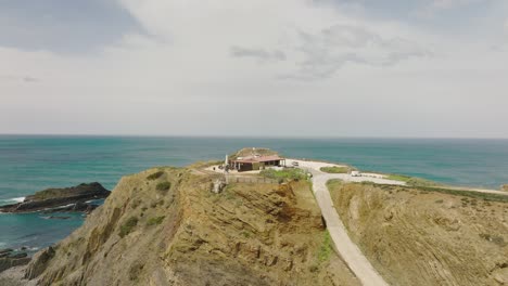 Aerial-shot-following-a-road-leading-to-a-viewpoint-over-a-turquoise-ocean