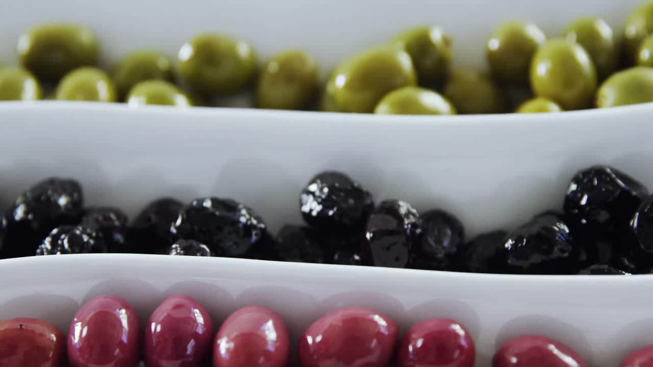 primer plano de aceitunas verdes, negras y rojas en escabeche
