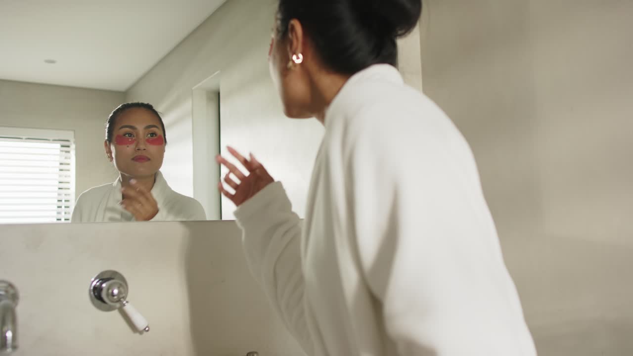 Donna asiatica entra in bagno con strumento per lisciare patch occhi allo specchio per la cura della pelle, spazio per la copia