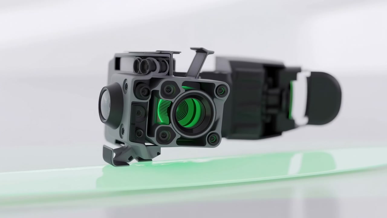 La luce verde si illumina gradualmente attraverso aperture frontali concentriche mentre l'involucro scuro dettagliato rimane nitidamente incorniciato sopra una superficie trasparente lucida con tenui riflessi da studio