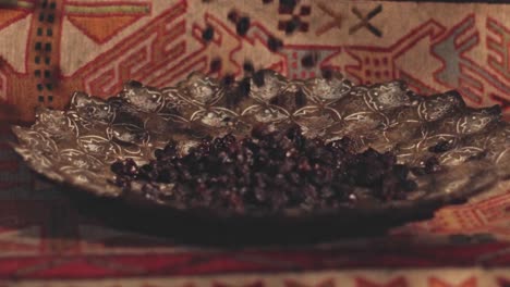 close-up shot of dried raisins falling into a beautifully decorated serving bowl