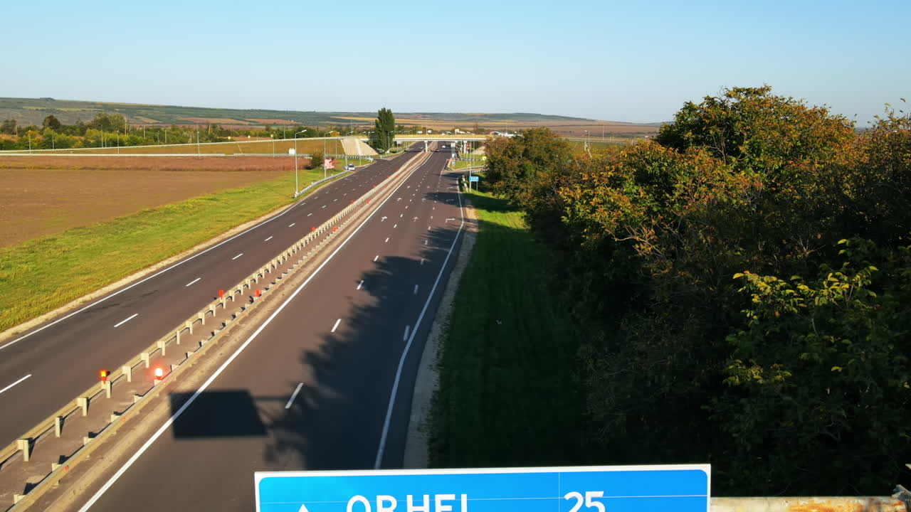 Aerial drone view of a road directions sign near a road junction with moving cars and nature around, greenery, Moldova