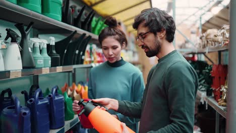 Portrait-of-positive-young-couple-at-the-garden-store,-choosing-sprayer