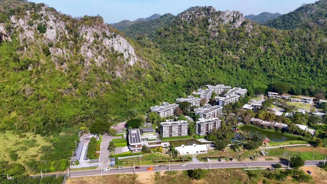 Một cảnh quay từ trên cao với góc máy cao lia qua một khu nghỉ dưỡng hiện đại nép mình trong những ngọn núi nhiệt đới tươi tốt của Thái Lan