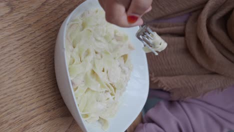 close-up of a person eating creamy pasta