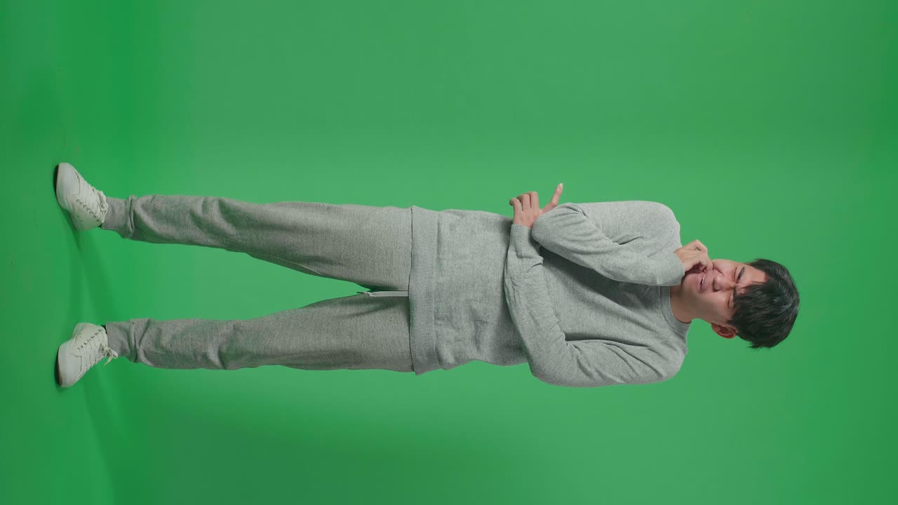 Full Body Of Asian Man Having Toothache While Standing In Front Of Green Screen Background