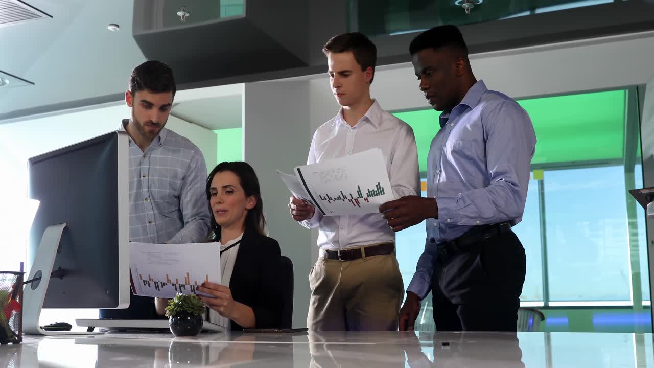 Business colleagues discussing over graph at desk 4k