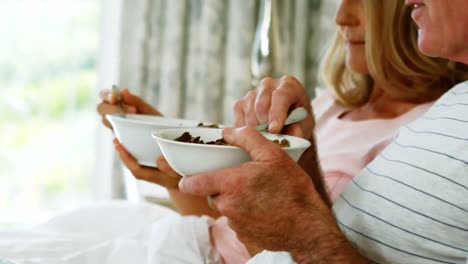 pareja sonriente tomando el desayuno en la cama