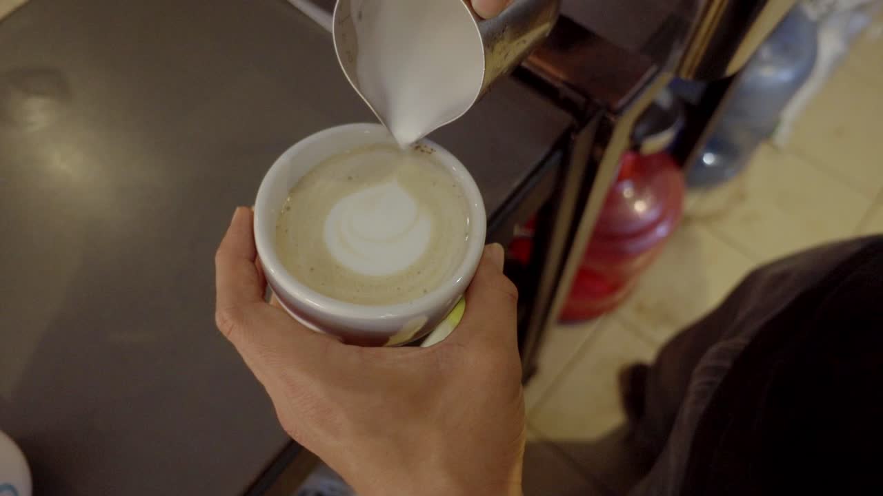 Barista aprendiendo a hacer arte latte a cámara lenta