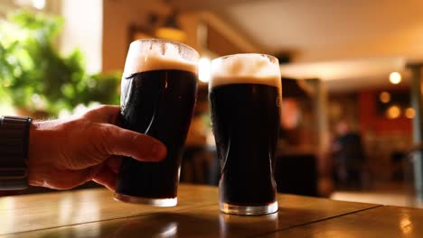 two pints of dark beer clinking together