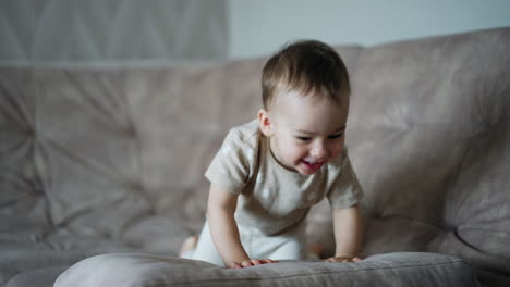 adorable smiling kid jumps on the big soft sofa. baby pushes the pillow happily.